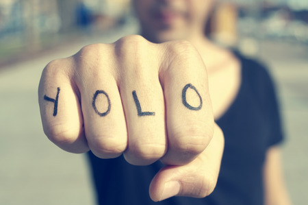 Close-up of a young man with the word YOLO, for You Only Live Once, tattooed in his hand