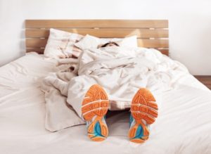 Woman sleeping in bed with running shoes on