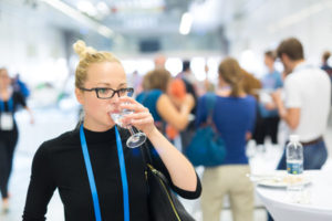 Beautiful woman drinking a glass of water during a networking event