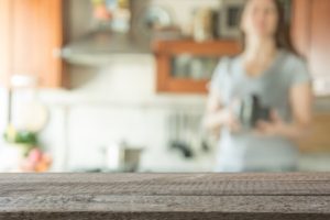 Blurred background with modern kitchen and woman preparing coffee