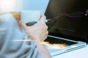 Young woman working on laptop holding a cup of coffee