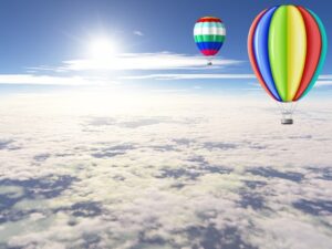 Beautiful balloons floating in the sunny sky above the clouds.